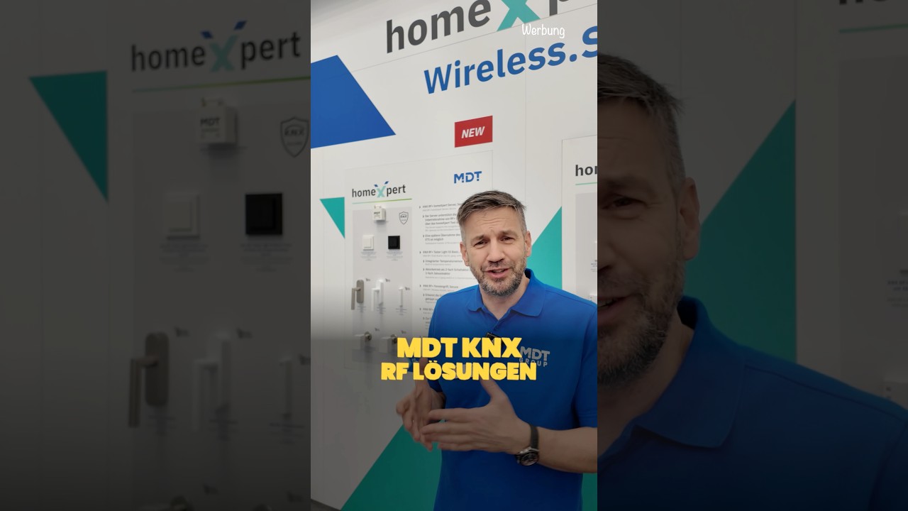 Vorschaubild: Tobias Haack im blauen Poloshirt mit MDT-Logo vor einer Ausstellungswand mit Tastern und Fenstergriffen, Logos von homeXpert und MDT, Schriftzüge „Wireless“, „NEW“ und „MDT KNX RF Lösungen“, oben rechts „Werbung“