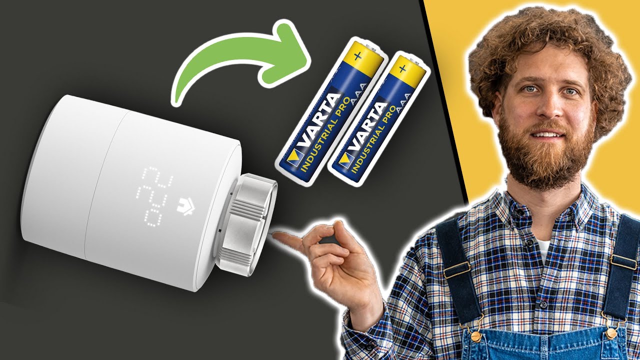 Vorschaubild: weißer smarter Heizkörperthermostat mit Anzeige, daneben zwei Batterien und ein grüner Pfeil, rechts Tobias Haack in kariertem Hemd und Latzhose, der auf den Thermostat zeigt