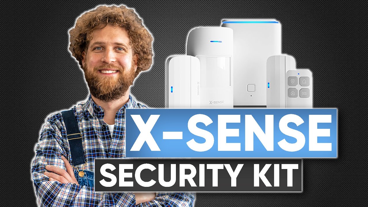 Vorschaubild: Tobias Haack mit verschränkten Armen neben mehreren weißen Geräten mit blauen Leuchten und einer kleinen Fernbedienung, Schriftzug „X-Sense Security Kit“